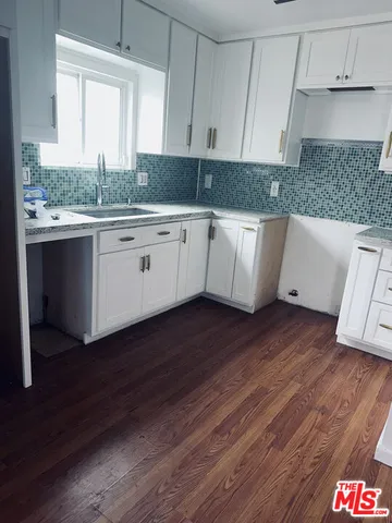 a kitchen with granite countertop wooden floors a sink and white cabinets