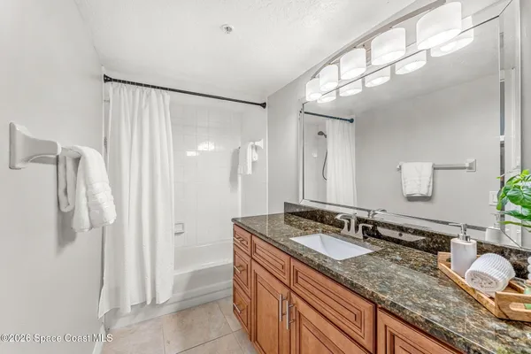 a bathroom with a granite countertop sink a mirror and a shower