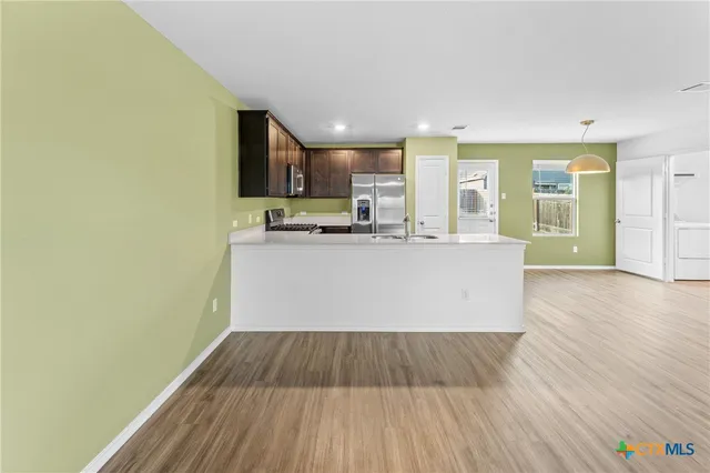 a view of a kitchen with kitchen island wooden floor center island and stainless steel appliances