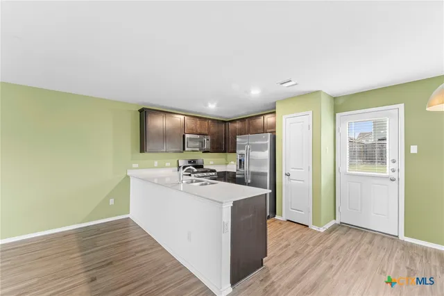 a view of a kitchen with kitchen island wooden floor center island and stainless steel appliances