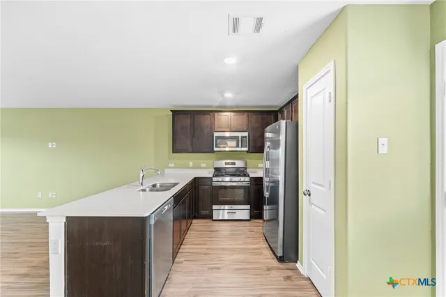 a kitchen with stainless steel appliances a sink stove and refrigerator