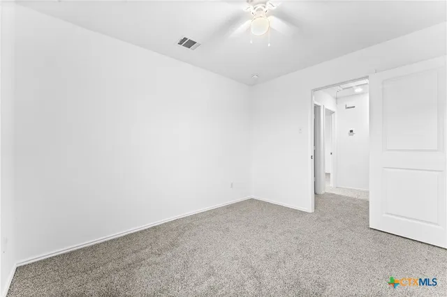 an empty room with a ceiling fan and a window