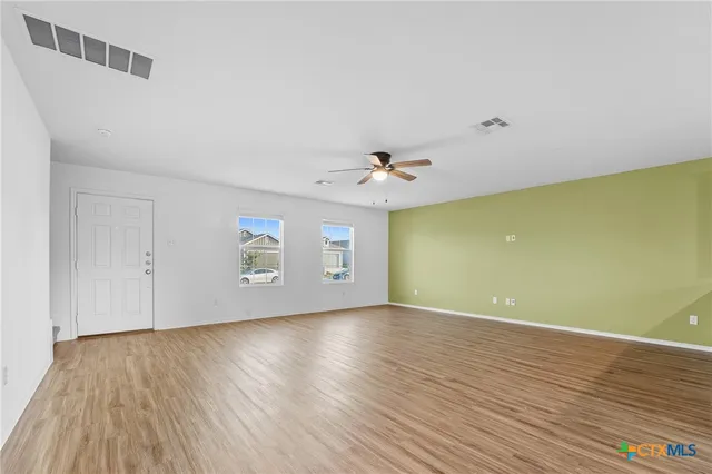 an empty room with wooden floor and windows