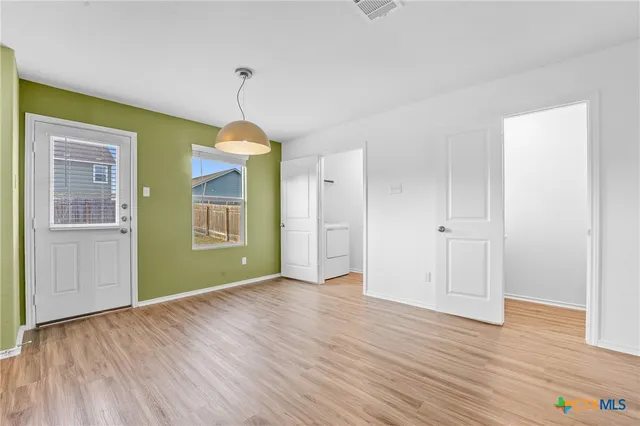 a view of an empty room with window and wooden floor