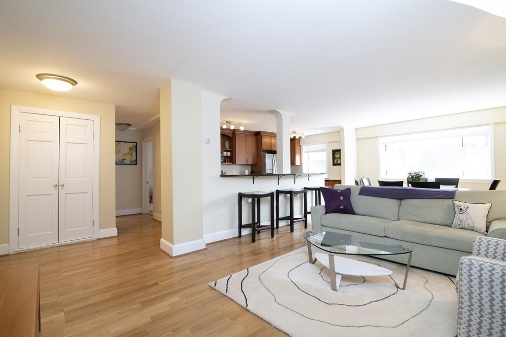 131 Sewall Avenue, Unit 37 Brookline, MA 02446 - Photo 5 of 27 a living room with furniture and a dining table with kitchen view