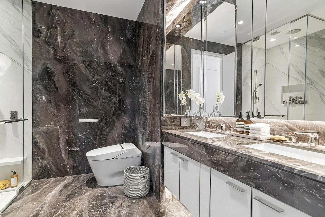 217 West 57th Street, Unit 43D Manhattan, NY 10019 - Photo 4 of 24 a bathroom with a granite countertop sink mirror vanity and toilet