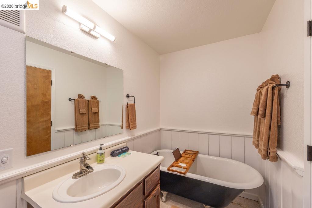 19266 Ferretti Road Groveland, CA 95321 - Photo 13 of 50 Bathroom with vanity, wainscoting, and a freestanding tub