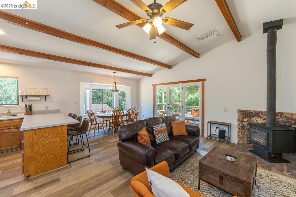19266 Ferretti Road Groveland, CA 95321 - Photo 3 of 50 Living area with a wood stove, ceiling fan, light wood-style flooring, and vaulted ceiling with beams