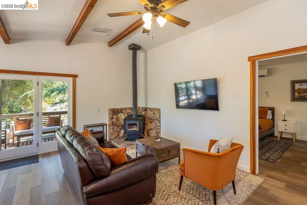 19266 Ferretti Road Groveland, CA 95321 - Photo 4 of 50 Living area featuring wood finished floors, a wood stove, ceiling fan, and vaulted ceiling with beams