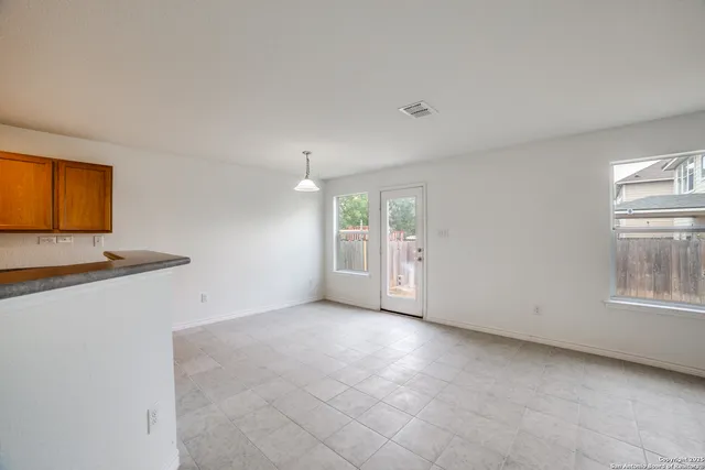 an empty room with windows and chandelier fan