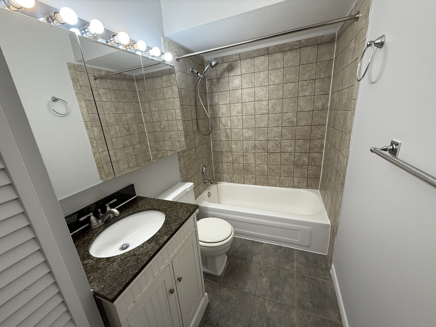 744 West Gordon Terrace, Unit 302 Chicago, IL 60613 - Photo 12 of 12 a bathroom with a granite countertop sink toilet a mirror a bathtub and shower