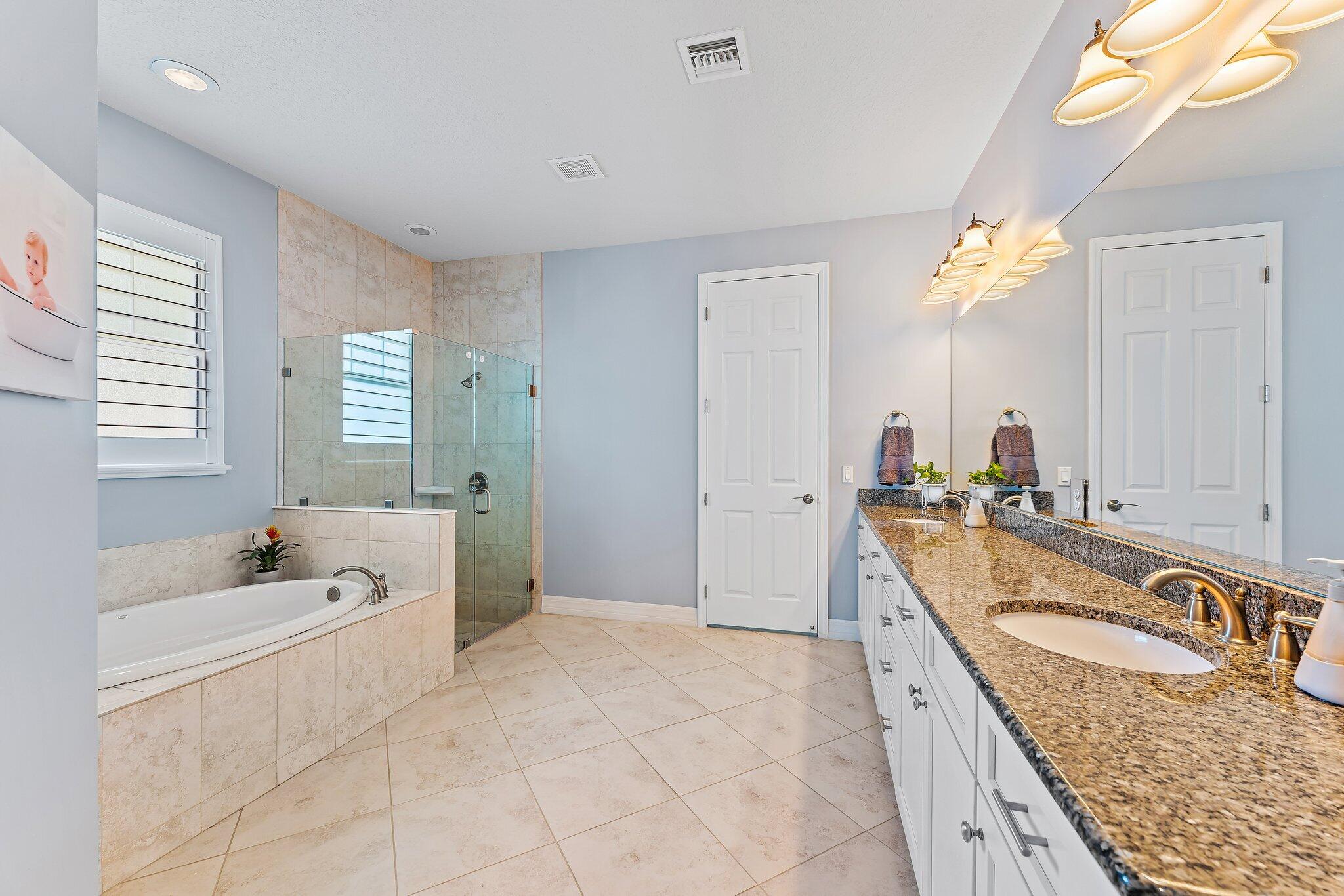 2835 East Mallory Boulevard Jupiter, FL 33458 - Photo 16 of 51 a spacious bathroom with a granite countertop tub a sink and a bathtub