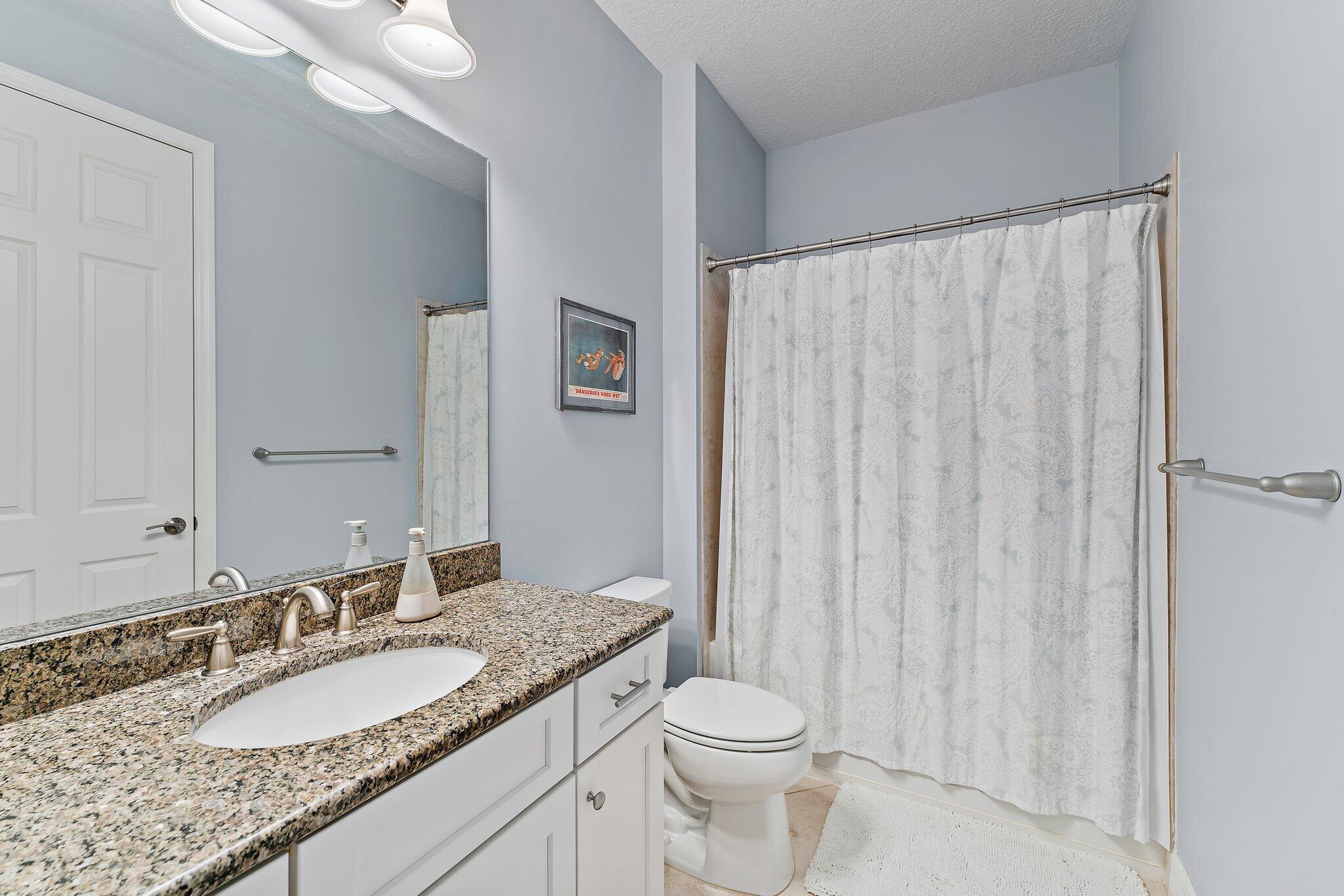 2835 East Mallory Boulevard Jupiter, FL 33458 - Photo 23 of 51 a bathroom with a granite countertop sink toilet and a mirror