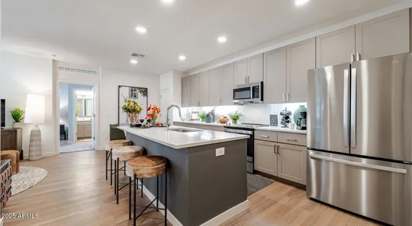 a kitchen with stainless steel appliances granite countertop a refrigerator a stove a sink a dining table and chairs with wooden floor