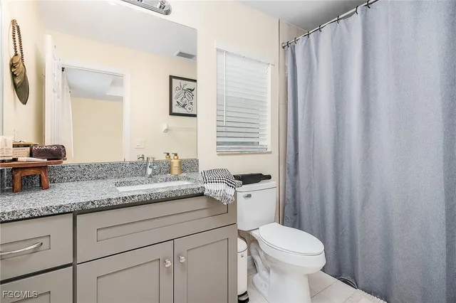 a bathroom with a granite countertop sink toilet and mirror