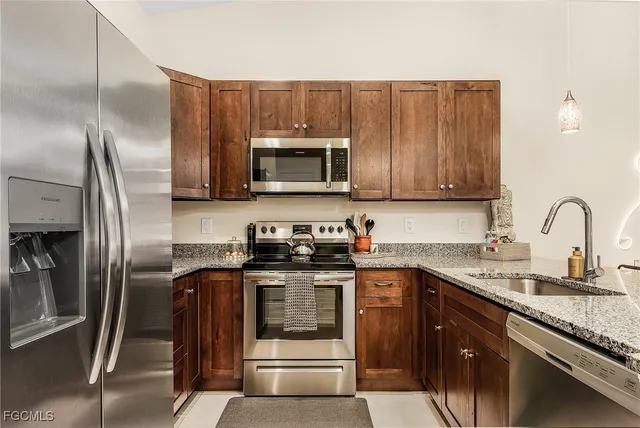 a kitchen with granite countertop a sink stainless steel appliances and cabinets