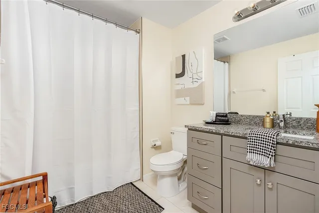 a bathroom with a granite countertop sink a toilet and a mirror
