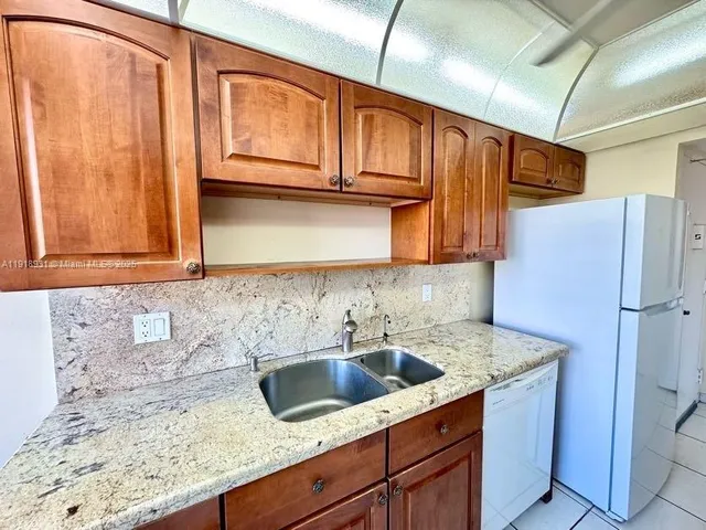 a kitchen with stainless steel appliances granite countertop a sink a refrigerator and cabinets