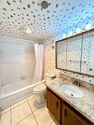 a bathroom with a granite countertop sink mirror vanity and toilet