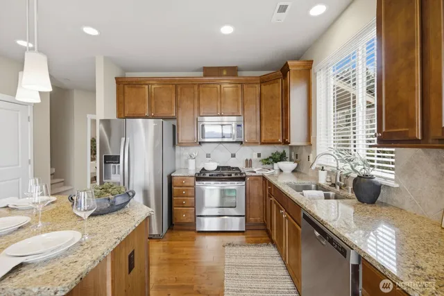 a kitchen with stainless steel appliances kitchen island granite countertop a refrigerator stove microwave and sink
