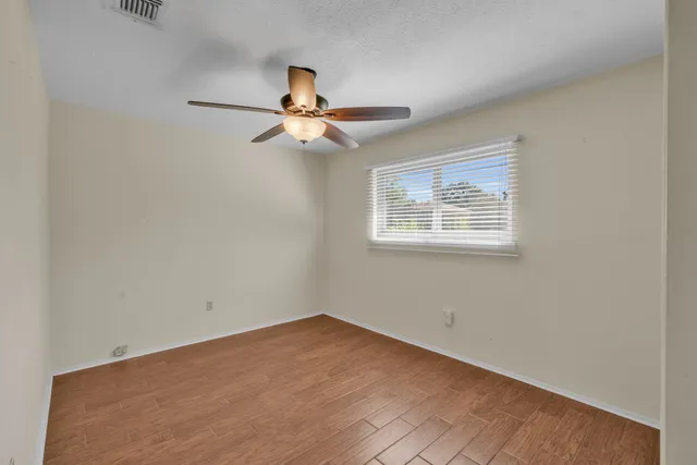an empty room with a window and a fan