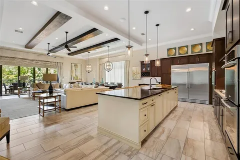 a large white kitchen with stainless steel appliances kitchen island granite countertop a large window and a counter space