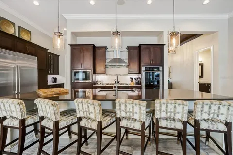 a kitchen with stainless steel appliances kitchen island granite countertop a dining table chairs and a refrigerator