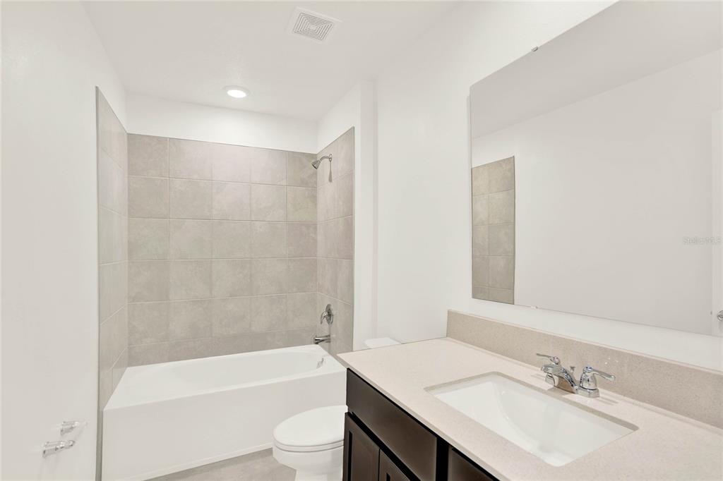 517 Bell Prairie Circle Lake Wales, FL 33859 - Photo 32 of 42 a bathroom with a granite countertop sink a toilet a mirror and bathtub