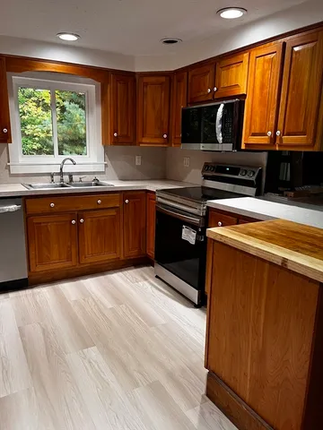a kitchen with stainless steel appliances granite countertop wooden cabinets a stove a sink and a microwave