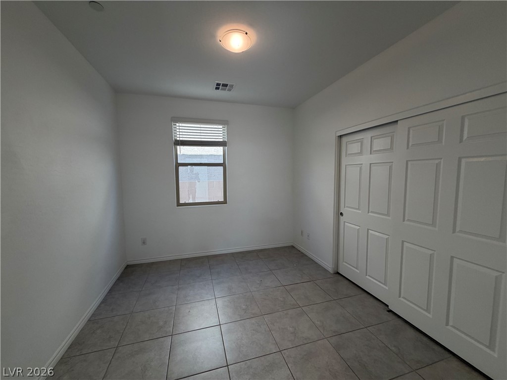 3228 Azalea Ridge Court Henderson, NV 89052 - Photo 21 of 28 A well-lit bedroom features durable tile flooring and convenient sliding closet doors.