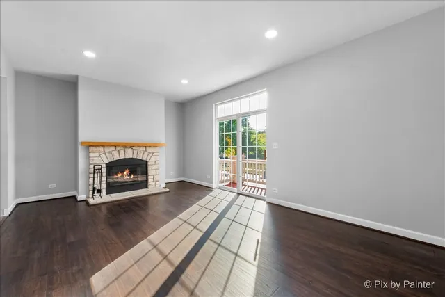 a view of an empty room with wooden floor fireplace and a window