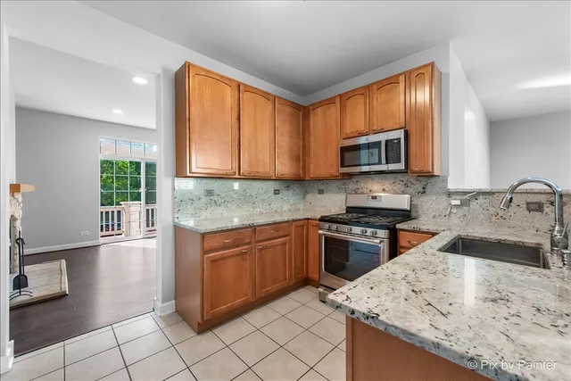 a kitchen with stainless steel appliances granite countertop a refrigerator a sink and a large window