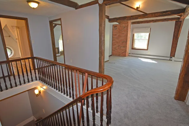 a view of a hallway with wooden floor and windows