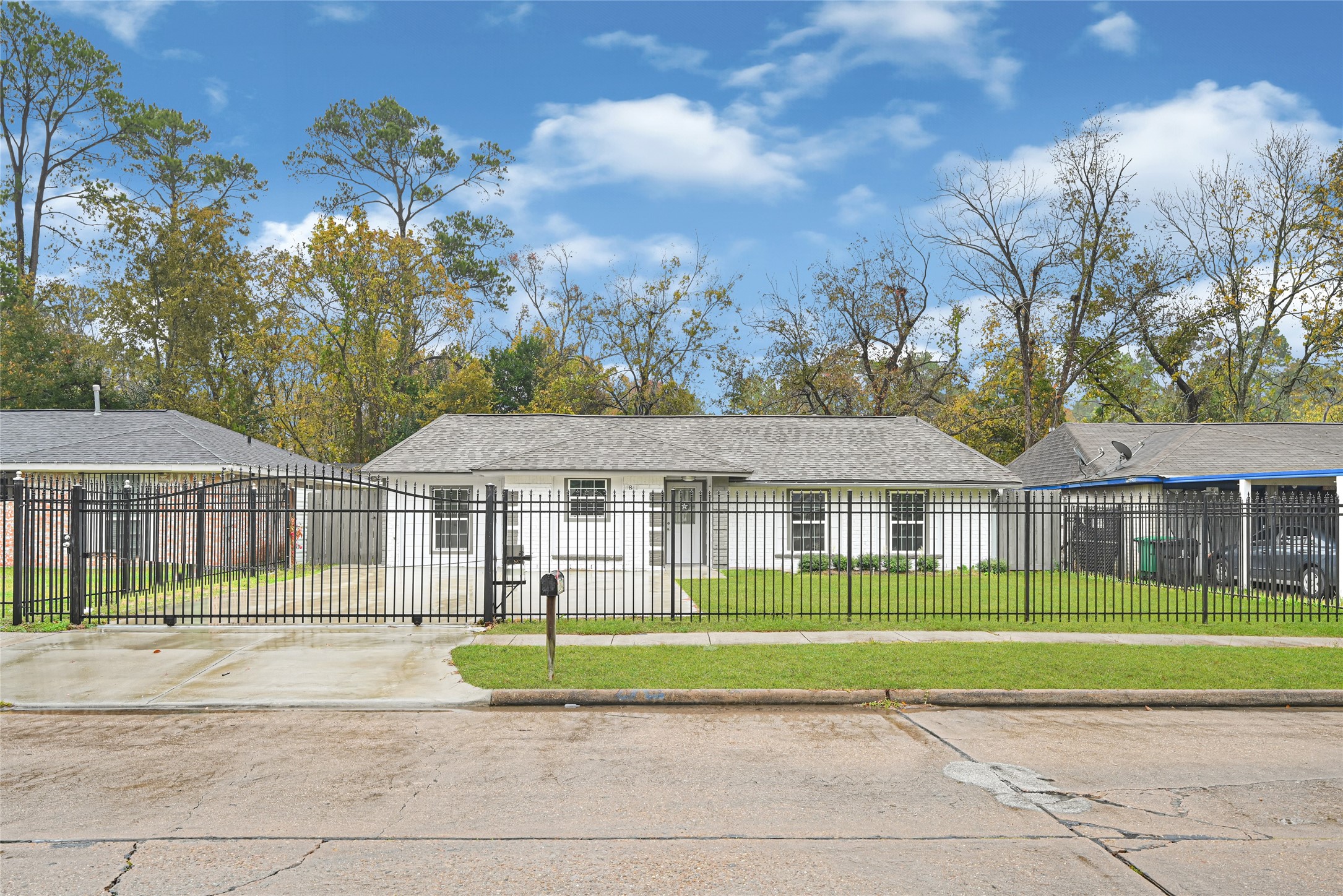 a view of a white house next to a yard and palm trees