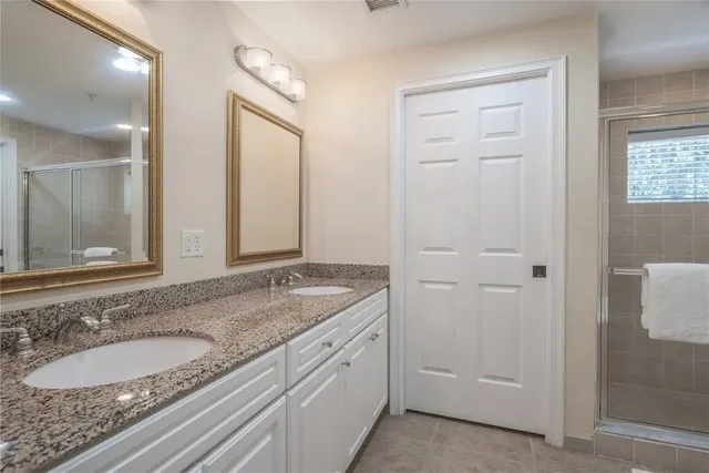 a bathroom with a granite countertop double vanity sink and a mirror