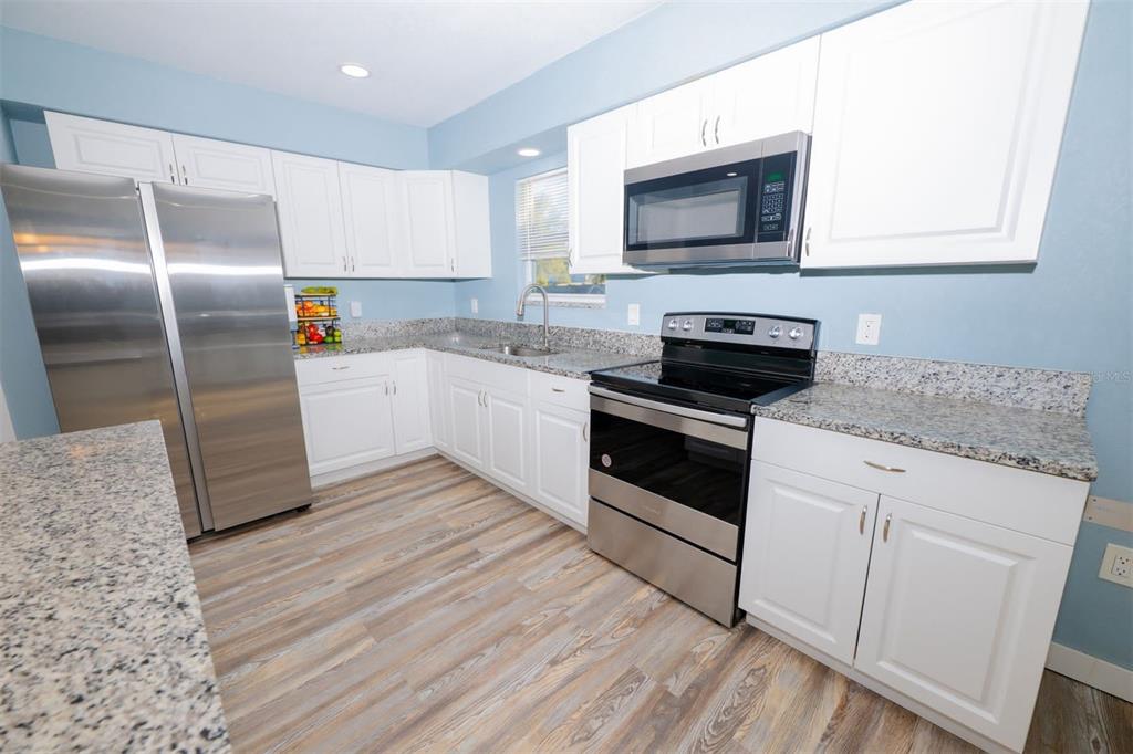 9330 Southeast Maricamp Road Ocala, FL 34472 - Photo 13 of 19 a kitchen with granite countertop a refrigerator and a stove top oven