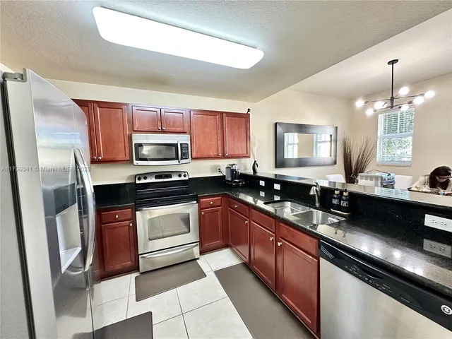 a kitchen with stainless steel appliances granite countertop a refrigerator a stove a sink and dishwasher