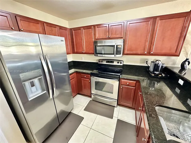 a kitchen with granite countertop a refrigerator stove and sink