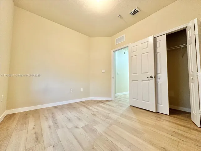 a view of a hallway with wooden floor and a bathroom