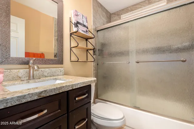 a bathroom with a granite countertop sink toilet and shower