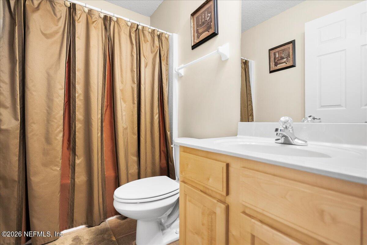 2489 Tall Cedars Road Fleming Island, FL 32003 - Photo 17 of 72 a bathroom with a sink a toilet and shower curtain