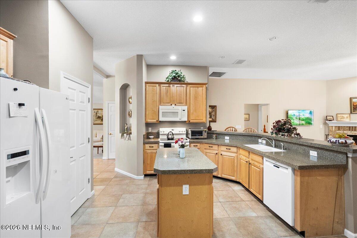 2489 Tall Cedars Road Fleming Island, FL 32003 - Photo 8 of 72 a large kitchen with a counter top space a sink a refrigerator a stove a microwave and cabinets