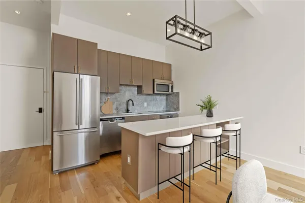 a kitchen with stainless steel appliances a refrigerator a sink a stove and white cabinets with wooden floor