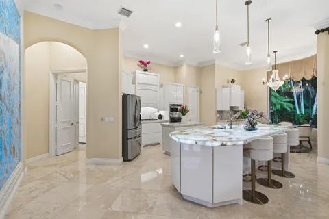 a large kitchen with kitchen island a white counter space a sink appliances and cabinets