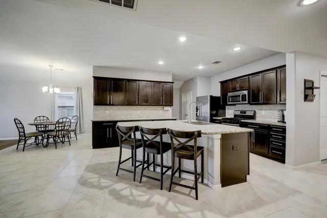 a kitchen with microwave a refrigerator and chairs