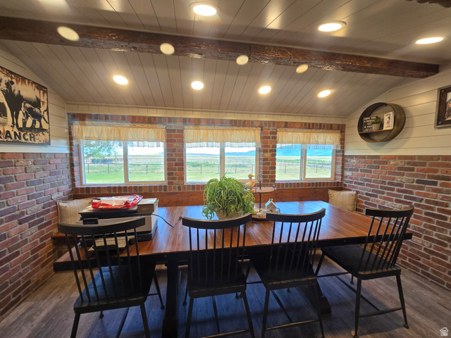 34200 Coulam Road Swan Lake, ID 83281 - Photo 10 of 24 Dining area featuring exposed brick walls, wood-finish flooring, a built-in wooden bench, a sloped ceiling with recessed lighting, and exposed ceiling beams