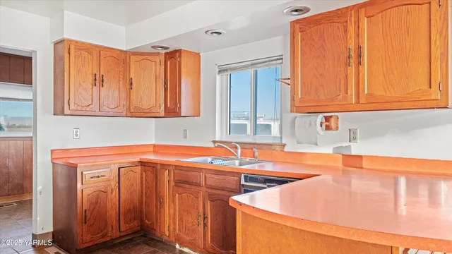 a utility room with stainless steel appliances granite countertop a sink and dishwasher a stove with wooden cabinets