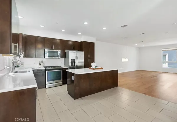 a kitchen with stainless steel appliances a stove a sink a microwave and a refrigerator