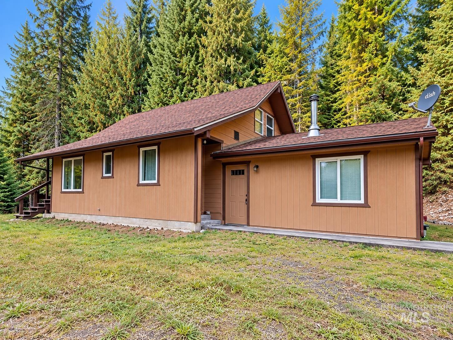 687 Big Cedar Road Kooskia, ID 83539 - Photo 1 of 37 Warm-toned siding exterior with white window frames, a brown shingle roof, and a covered porch with dark wood stairs