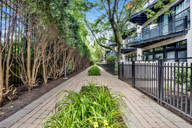 a front view of a building with a garden and trees